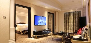 A hotel room with a bed, a television, a desk, and a large window with curtains.