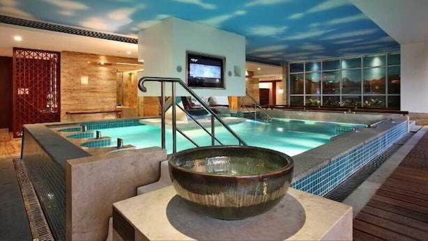 Ein Hallenbad mit Deckenfresko, einem Fernsehbildschirm und einem Holzdeck.