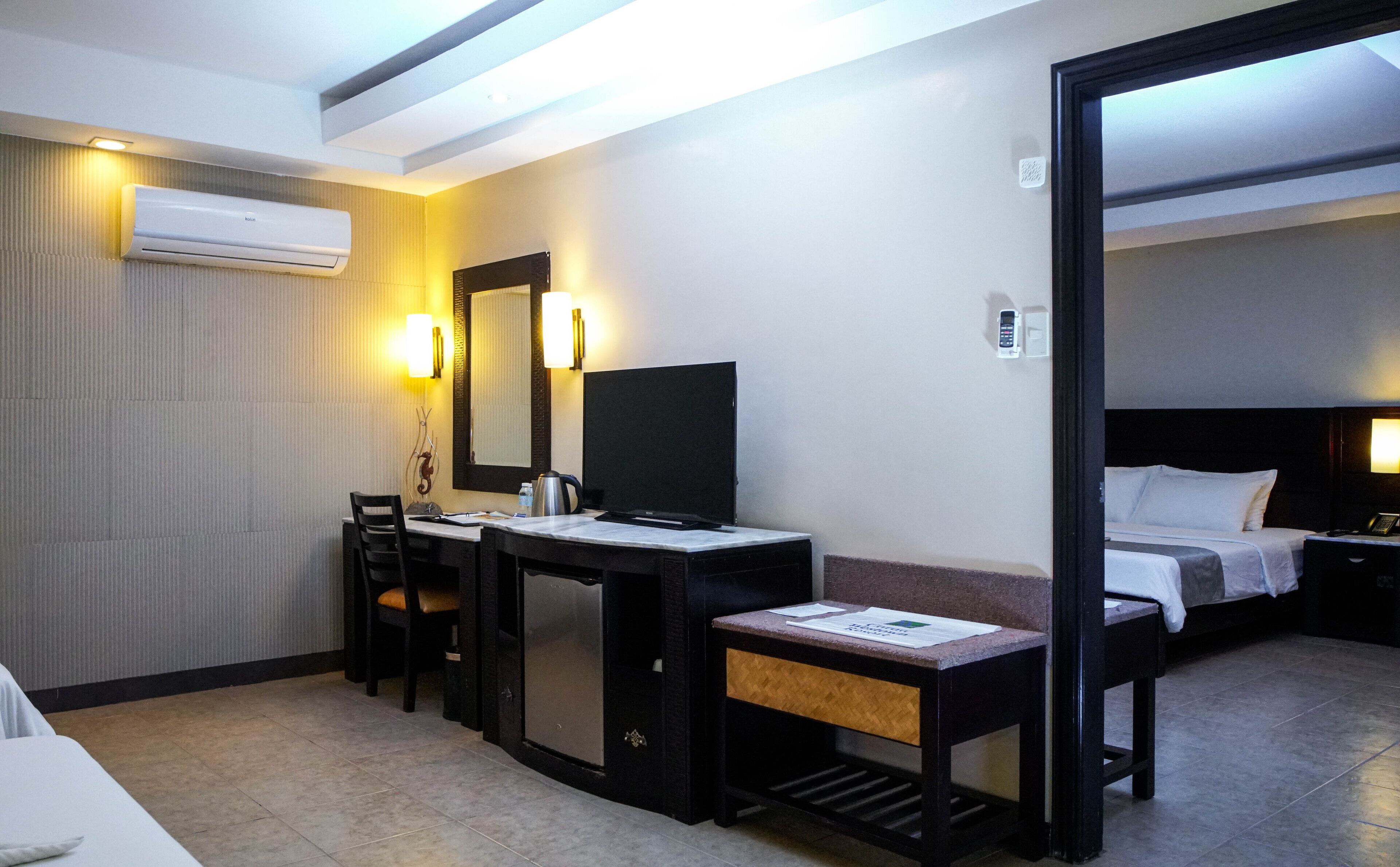 Habitación de hotel con escritorio, silla, cama y un espejo grande.
