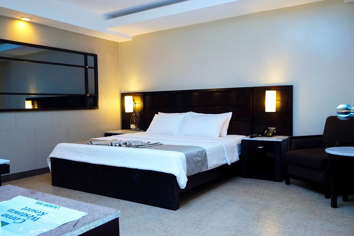 A hotel room with a large bed, bedside tables, a desk, and a chair.