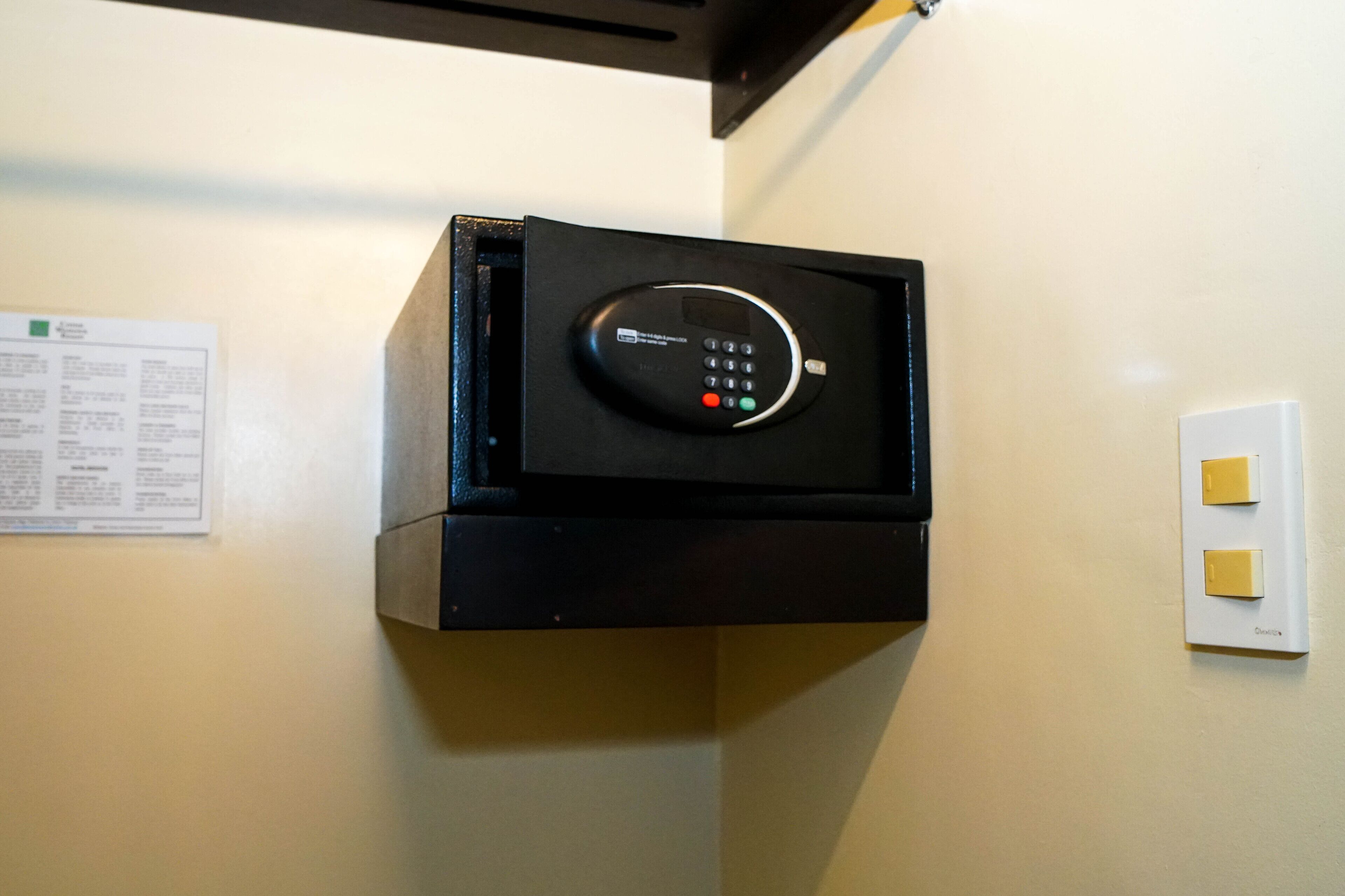 Una caja fuerte negra fijada a la pared, con un panel de control.