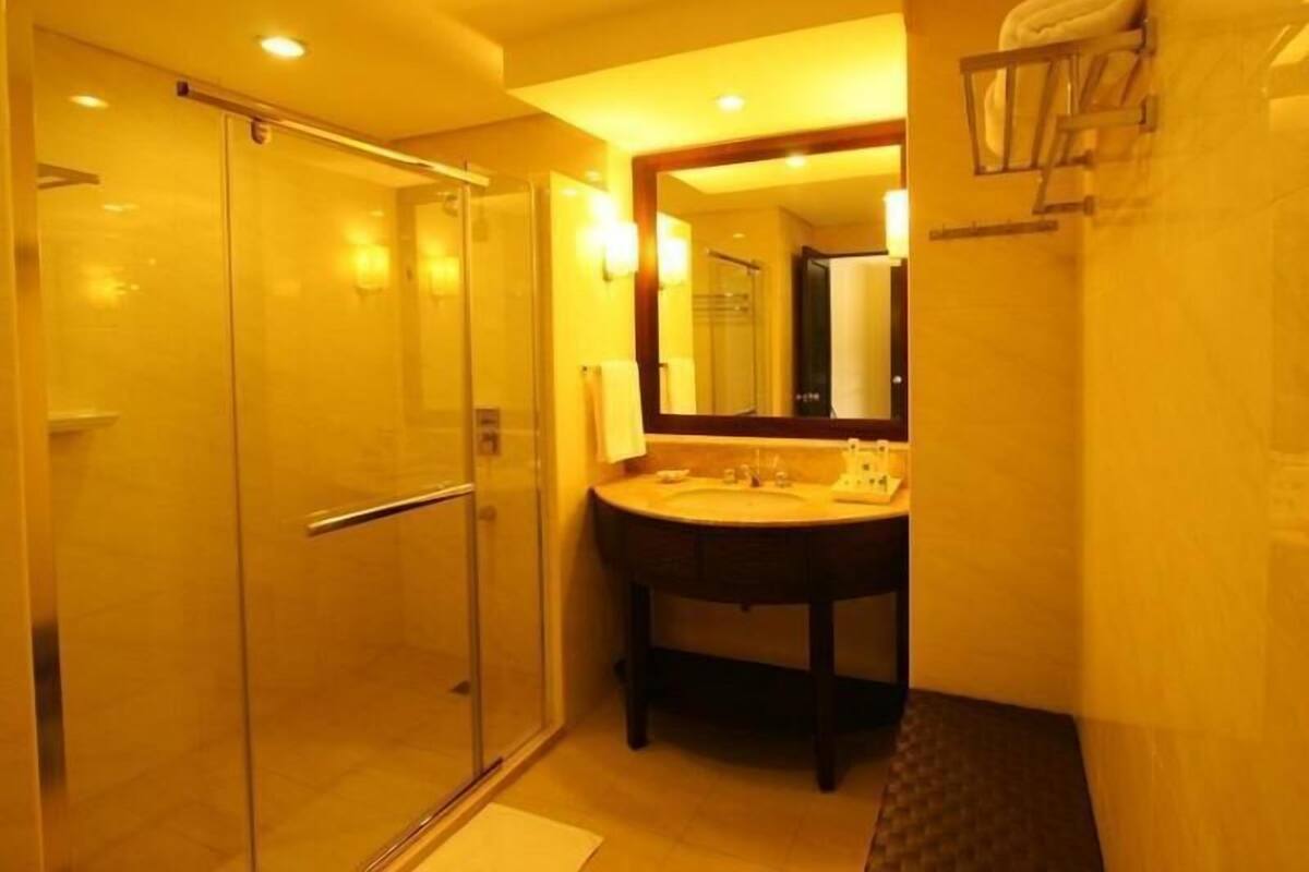 A bathroom with a glass shower enclosure, a sink with a mirror, and a towel rack.