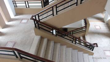 A multi-level interior with a central staircase, handrails, and a patterned floor.