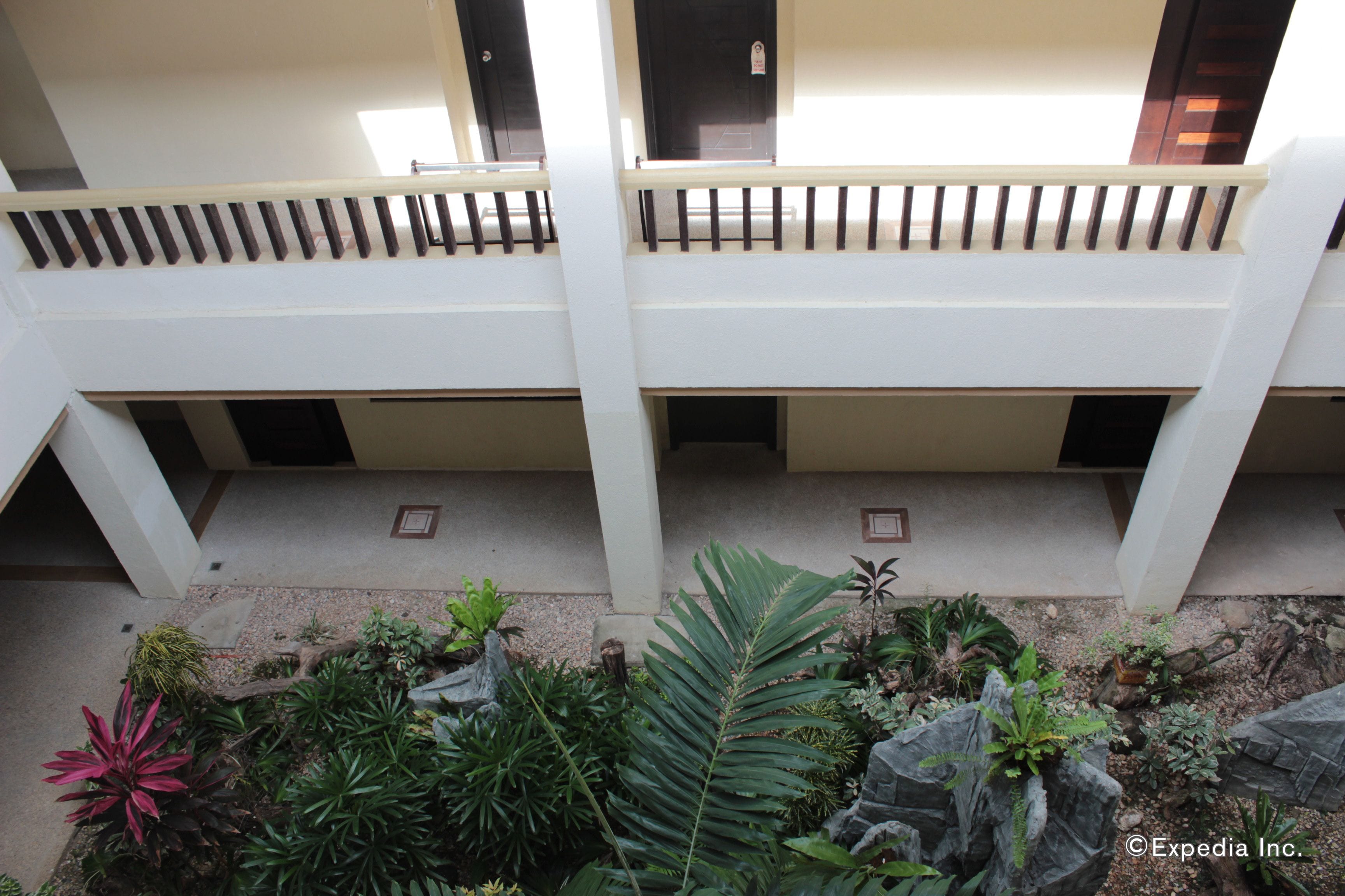 A multi-level building with balconies and a landscaped garden area.