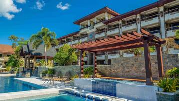 Et hotel med swimmingpool, udendørs siddepladser og et overdækket område med pergola.