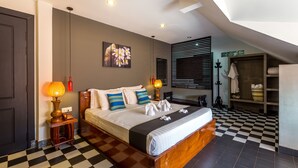 Une chambre d’hôtel moderne avec un sol à carreaux, un grand lit recouvert de draps blancs, une œuvre d’art accrochée au mur et une lucarne au plafond.