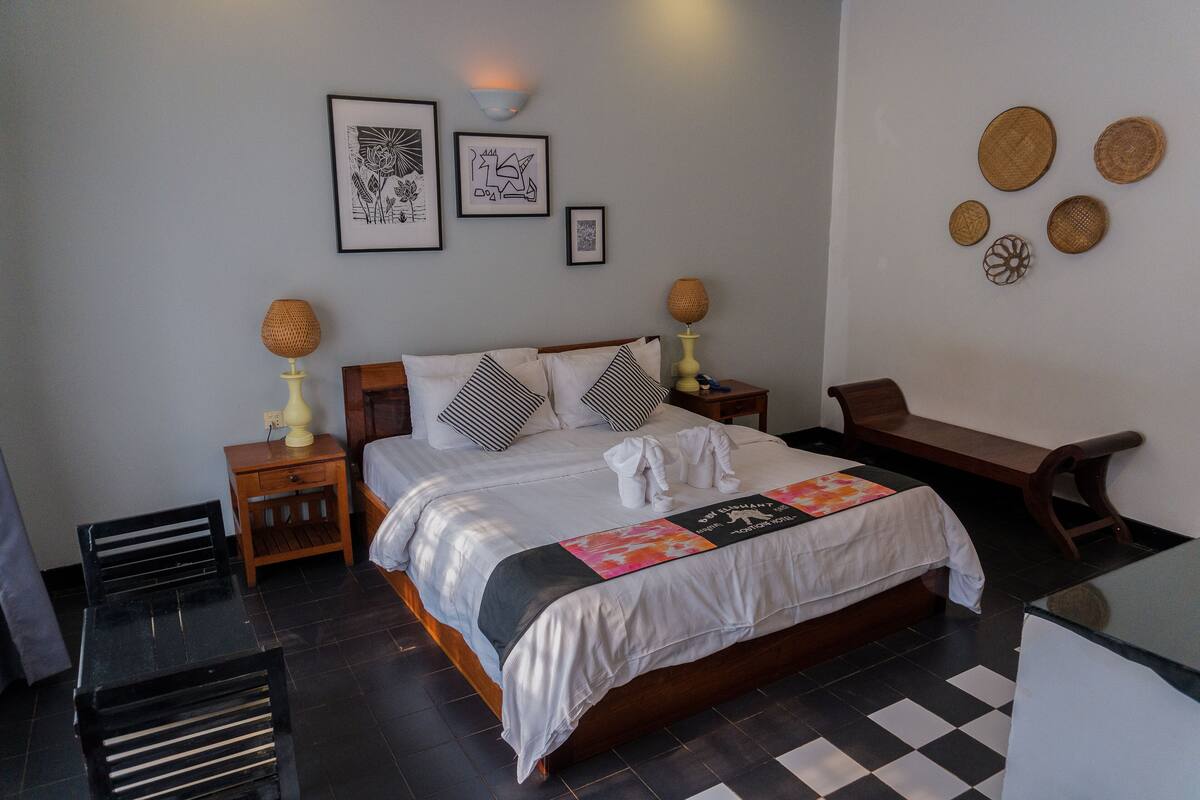 Un dormitorio ordenado con cama, mesitas de noche, un banco y decoración en las paredes.