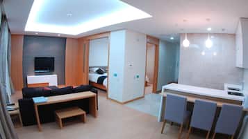 Una moderna camera d'albergo con zona living, angolo cottura e camera da letto.