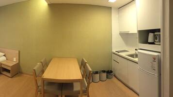A hotel room with a bed, a desk, a television, a refrigerator, and a window with curtains.