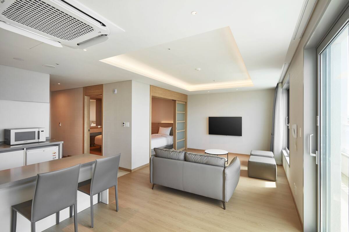 Une chambre d’hôtel moderne équipée d’une kitchenette, d’un canapé, d’un coin repas et d’une télévision.