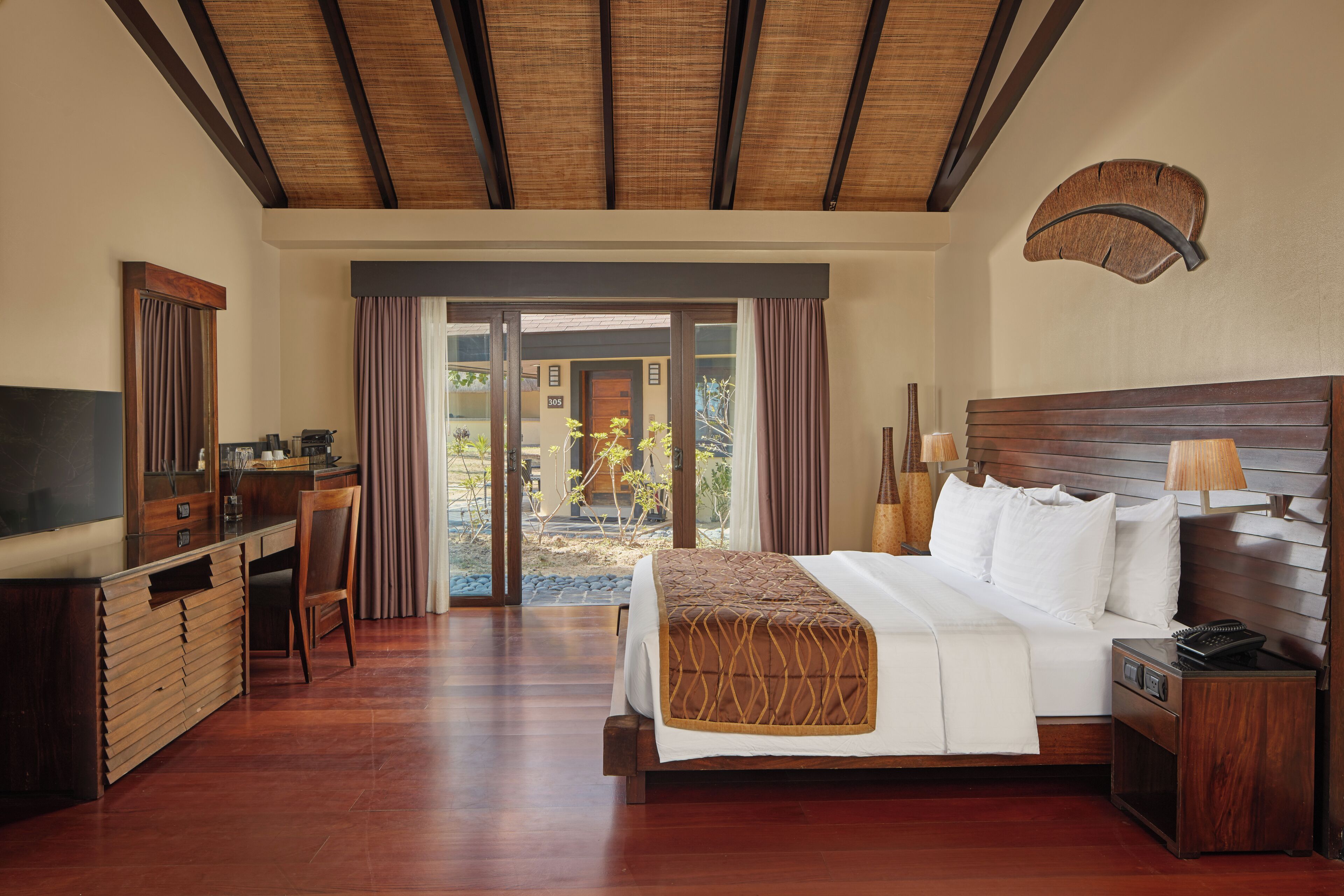 Habitación de hotel con cama, escritorio, televisor y vistas al exterior.