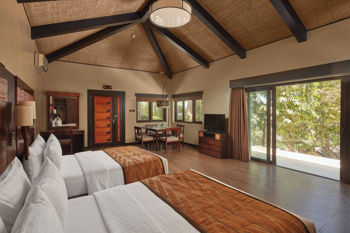 A spacious room with a high ceiling, a dining area, and a large window providing a view of the outdoors.