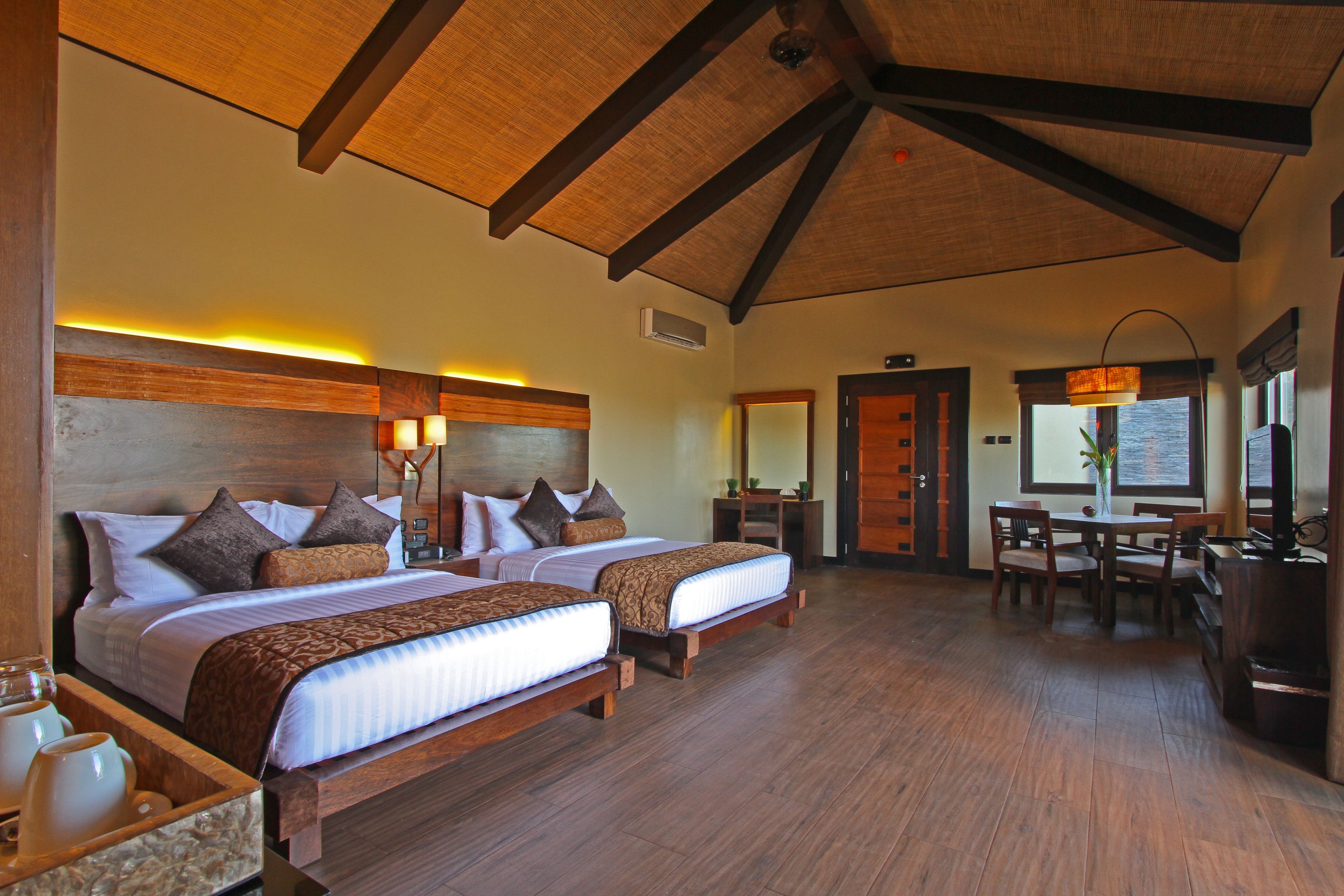 A hotel room with two beds, a dining area, and a kitchen.