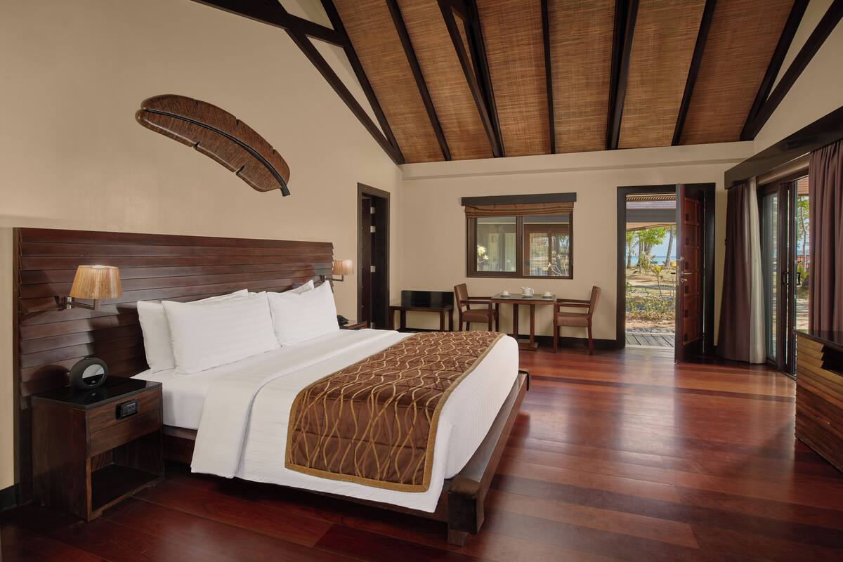 A hotel room with a large bed, a desk, and a window.