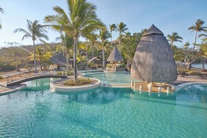 Una piscina al aire libre, sombrillas, sillones reclinables de piscina