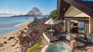 Una propiedad frente a la playa con jacuzzi, mobiliario exterior y vistas al océano.
