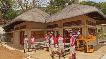 A building with a thatched roof, a sign reading "Pawikani", and a group of people standing in front.