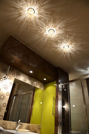 A modern bathroom with a large mirror, a sink, and a shower area. - Angel Plaza Apartments (Kraków)