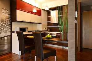 A modern kitchen with a dining area, featuring a microwave, stove, and a bowl of apples on the counter.