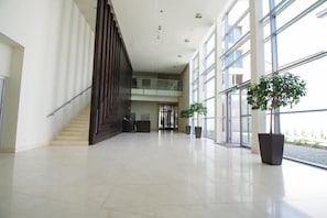 A spacious lobby with a staircase, large windows, and potted plants.
