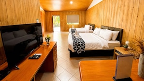 A modern hotel room with wooden paneling, a large bed, a TV, and a desk. - Forest Crest Nature Hotel and Resort (Nasugbu)