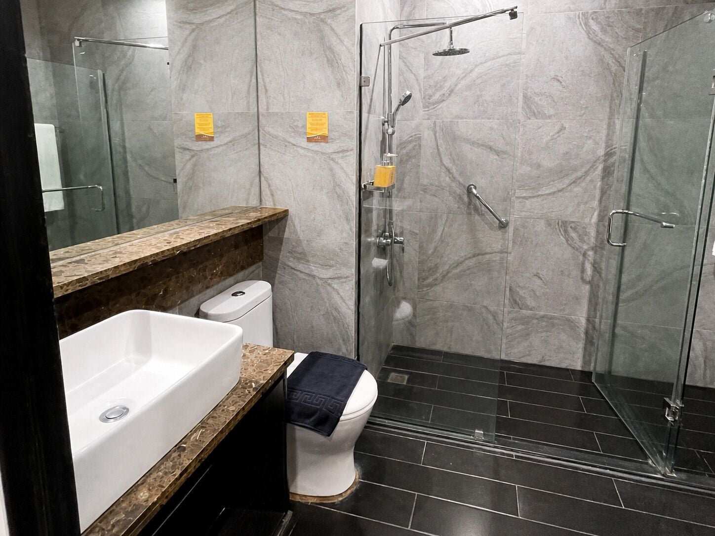 A modern bathroom with a glass shower enclosure, a white toilet, and a marble countertop.