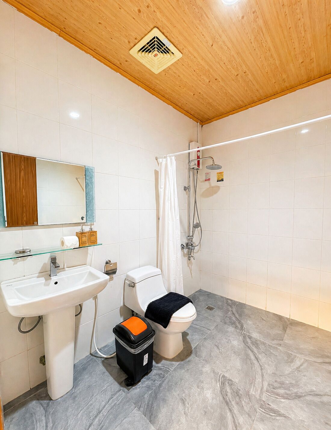 Un baño con lavamanos, inodoro, ducha y espejo.