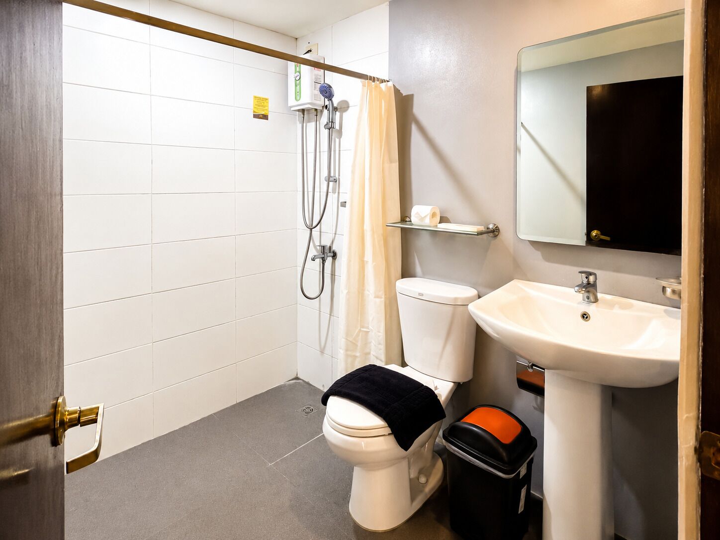 A bathroom with a shower, toilet, sink, and a mirror.