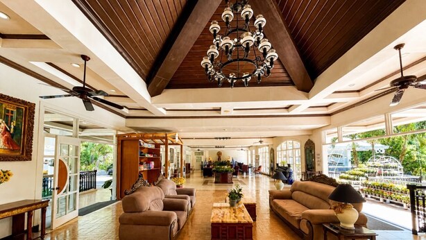 A spacious living area with wooden flooring, a chandelier, ceiling fans, and a view of the outdoors. - Forest Crest Nature Hotel and Resort (Nasugbu)