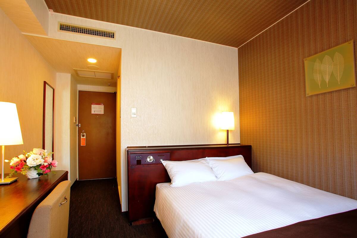 Ein Hotelzimmer mit Bett, Nachttisch, Lampe und einem Wandbild.