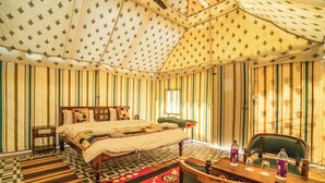 Una habitación con una cama, una mesa y sillas, y paredes a rayas.
