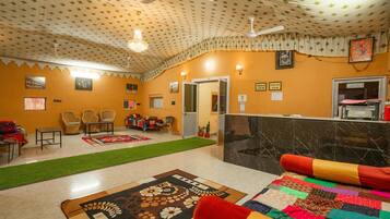 Cozy room with a bed, two chairs, and a small table, featuring a ceiling fan and a patterned rug.