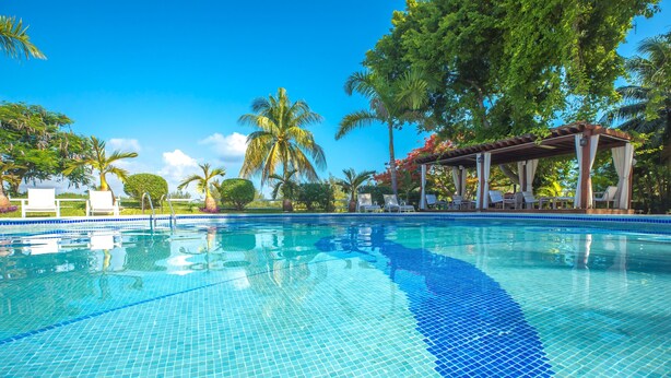 A clear blue swimming pool with tiled edges, surrounded by palm trees and lounge chairs. - Las Gaviotas Hotel & Suites (Cancun)