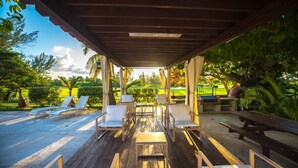 A covered outdoor seating area with lounge chairs and tables, overlooking a well-maintained garden and golf course. - Las Gaviotas Hotel & Suites (Cancun)