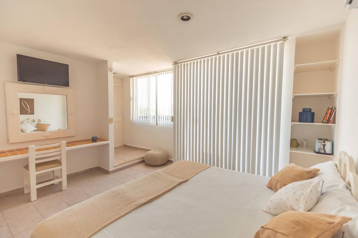 A bedroom with a bed, a desk, a chair, a TV, and a wardrobe.