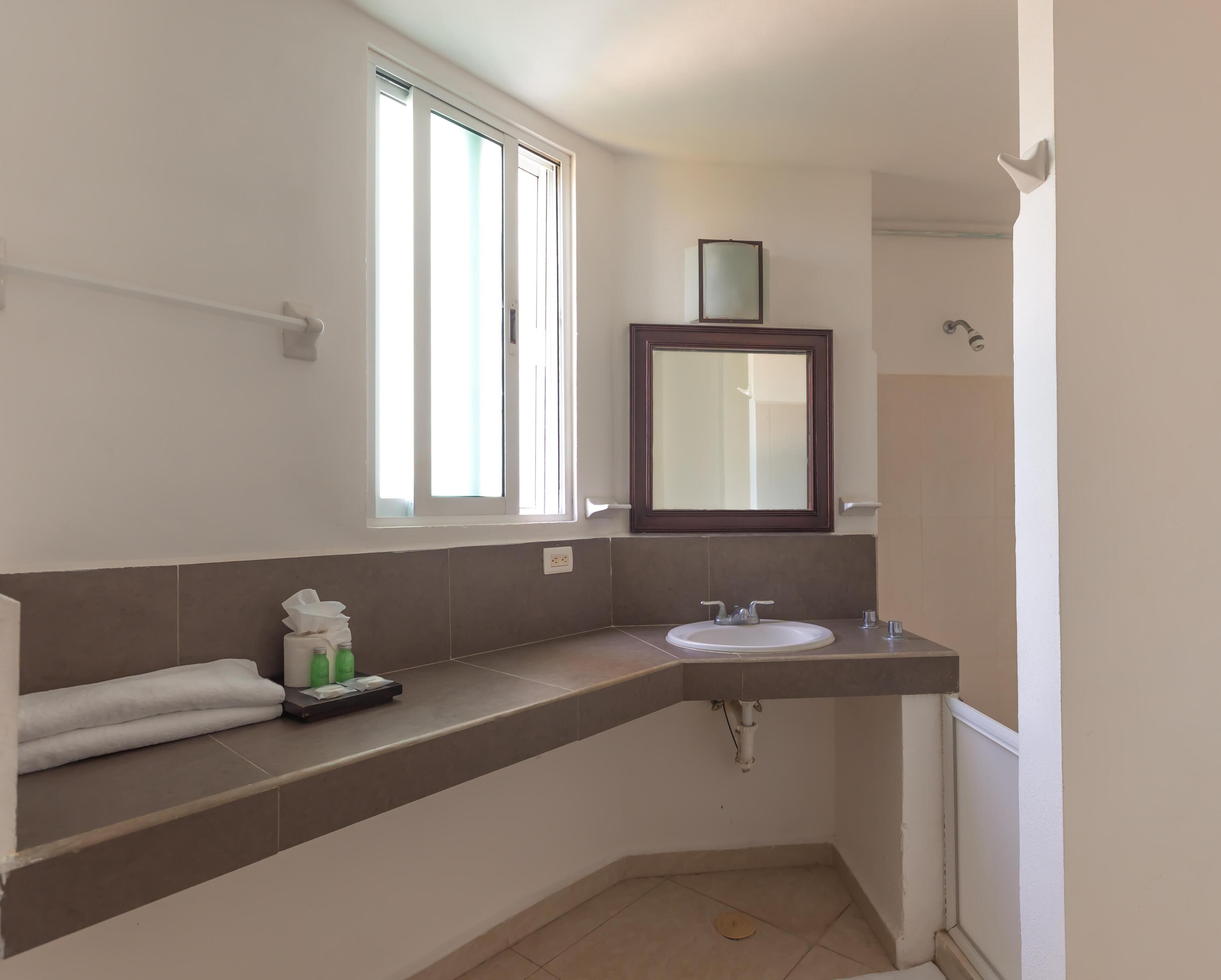 A bathroom with a window, a sink, a mirror, and a towel rack.