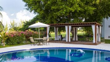 Una piscina al aire libre, sombrillas, sillones reclinables de piscina