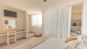 A bedroom with a bed, a desk, a chair, a mirror, and a window with blinds. - Las Gaviotas Hotel & Suites (Cancun)