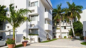 A modern white building with balconies, potted plants, and a clear blue sky. - Las Gaviotas Hotel & Suites (Cancun)