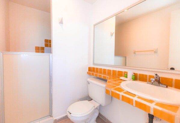Un baño con inodoro, lavamanos y espejo.