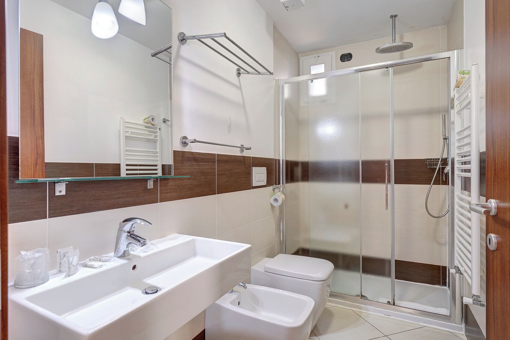 A modern bathroom with a glass shower enclosure, a white sink, and a bidet.