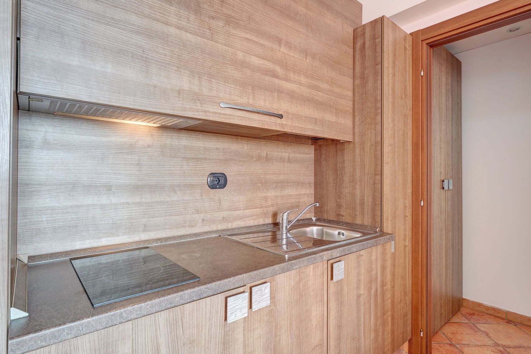 A kitchen with a built-in sink, wooden cabinets, and a countertop.