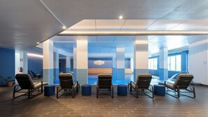 A modern indoor relaxation area with five lounge chairs, a blue-tiled floor, and a central water feature. - Ai Pozzi Village Resort & SPA (Loano)