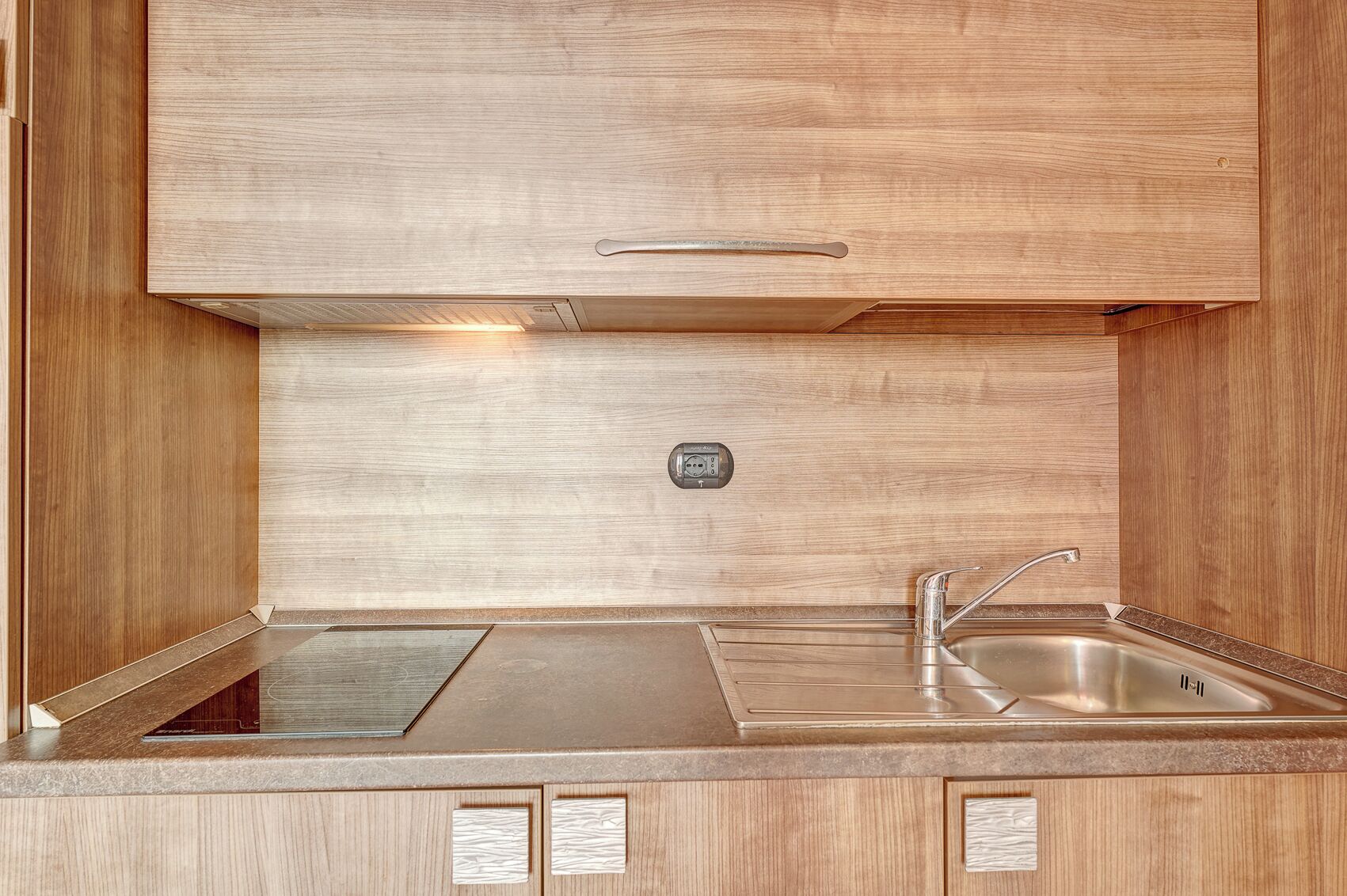 A compact kitchen with a built-in stove, a sink, and a control panel.