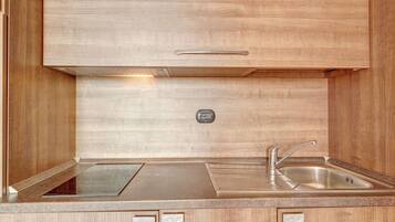 A compact kitchen with a built-in stove, a sink, and a control panel.