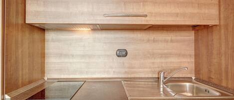 A compact kitchen with a built-in stove, a sink, and a control panel.