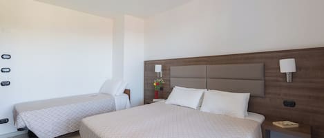 A hotel room with two single beds, a wooden headboard, bedside lamps, a nightstand, and a small table.