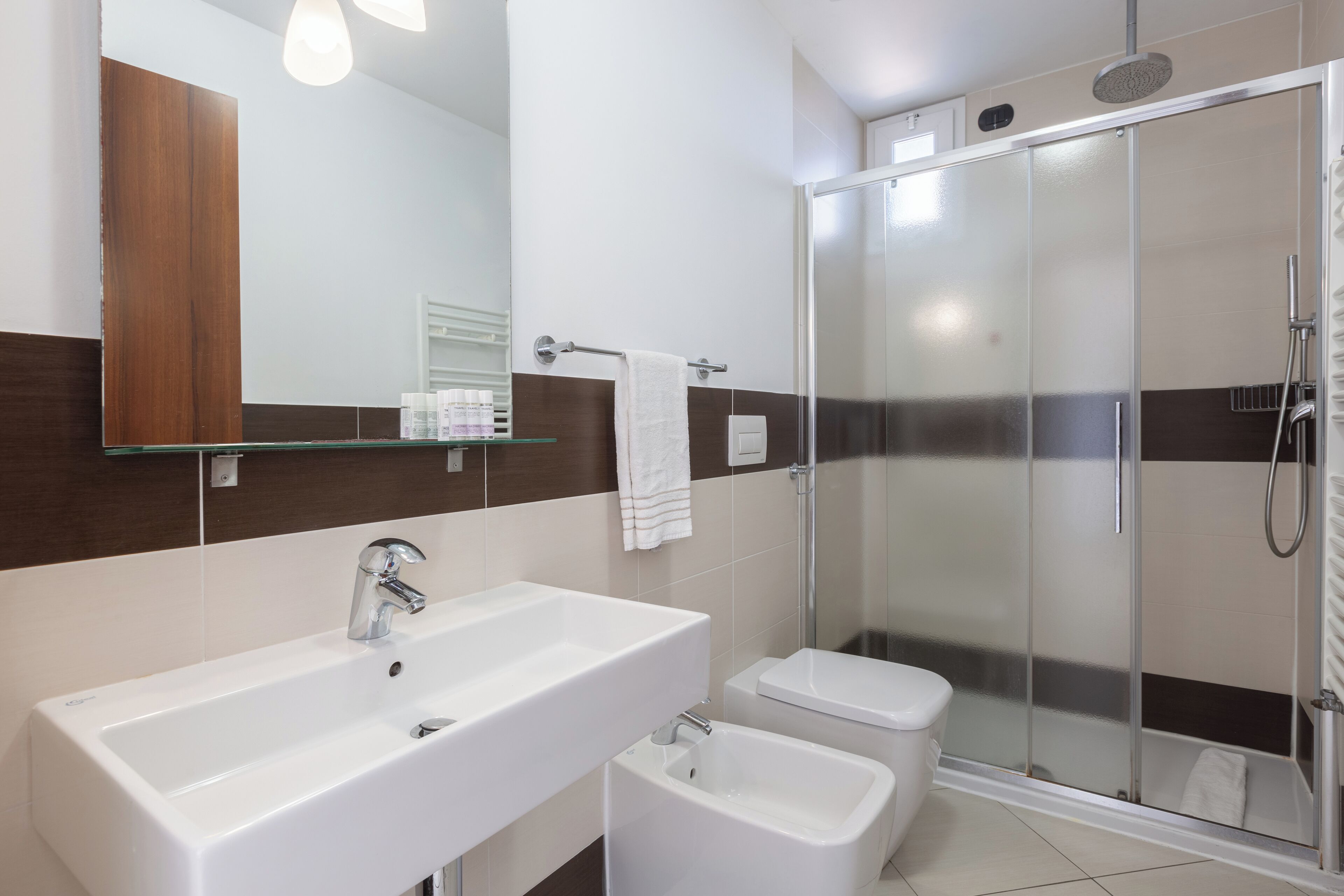 A modern bathroom with a large sink, toilet, and a glass-enclosed shower area.