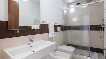 A modern bathroom with a large sink, toilet, and a glass-enclosed shower area.