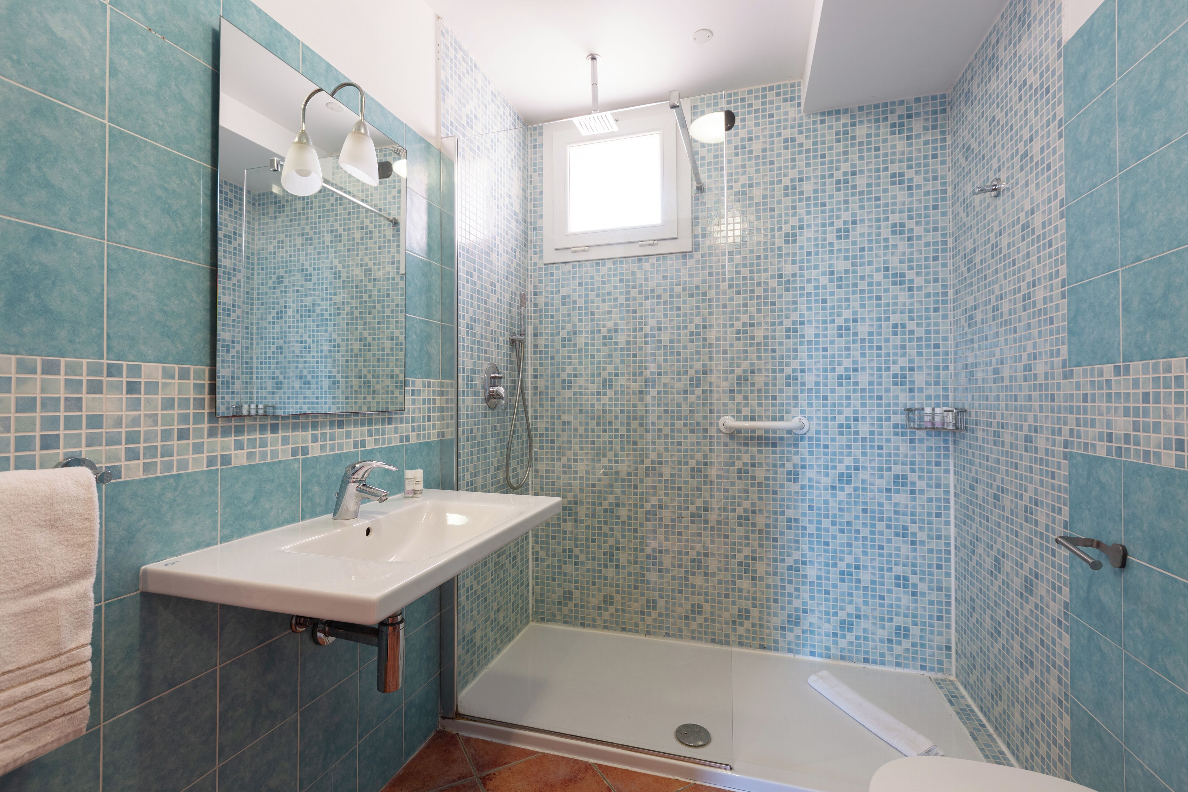 Une salle de bain avec un lavabo, un miroir, une douche et des murs carrelés.